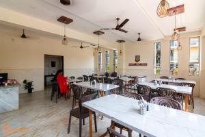 un restaurant avec des tables et des chaises et une femme assise à une table dans l'établissement Arnnas Resort Diveagar, à Diveagar