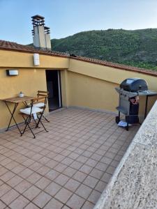 eine Terrasse mit einem Grill, einem Tisch und Stühlen in der Unterkunft La Mansarda Di Cecco in Avezzano