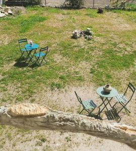 2 tables et chaises dans une cour avec pelouse dans l'établissement Le p'tit coin dans les vignes, à Restigné