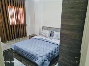 um quarto com uma cama com lençóis azuis e uma janela em Superbe logement Majida boulila em Sfax