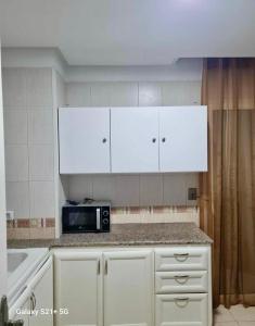 uma cozinha com armários brancos e um micro-ondas em Superbe logement Majida boulila em Sfax