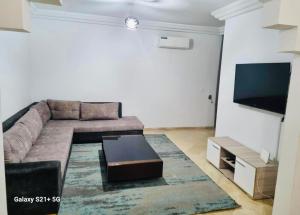 uma sala de estar com um sofá e uma televisão de ecrã plano em Superbe logement Majida boulila em Sfax
