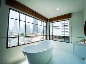 a white bath tub in a bathroom with windows at SO Zen Hotel Silom Bangkok in Bang Rak
