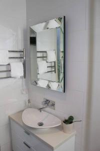 a white bathroom with a sink and a mirror at Stylish 2-Bed Terrace with Private Deck in Melbourne