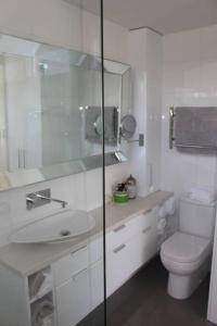 a white bathroom with a toilet and a sink at Stylish 2-Bed Terrace with Private Deck in Melbourne