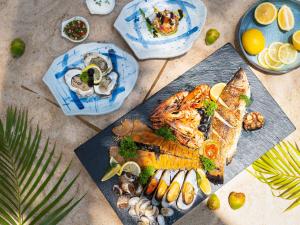 ein Teller mit Essen mit Fisch und Gemüse auf einem Tisch in der Unterkunft Explorar Koh Samui - Adults Only Resort and Spa in Mae Nam