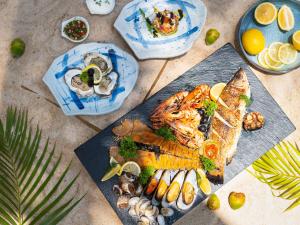 a plate of food with fish and vegetables on a table at Explorar Koh Samui - Adults Only Resort and Spa in Mae Nam