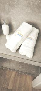 two white towels sitting on a counter in a bathroom at Central Apartments Neptun Park 1 & Parking in Gdańsk