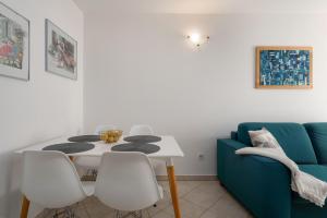 uma sala de jantar com uma mesa e um sofá azul em Degrassi Square Apartments em Vrsar
