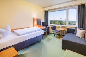 um quarto de hotel com uma cama, uma secretária e um sofá em Garden Hotel Krefeld em Krefeld