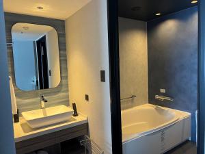 a bathroom with a tub and a sink and a mirror at Grand Mercure Beppu Bay Resort & Spa in Beppu