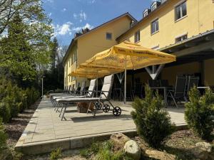 patio z krzesłami i parasolami obok budynku w obiekcie Maiers Hotel w mieście Bayerisch Eisenstein