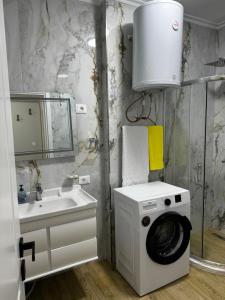 a bathroom with a washing machine next to a sink at GOLEM Best Apartment in Golem