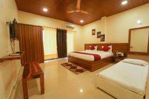 a bedroom with two beds and a flat screen tv at Trattino Resorts in Panchgani