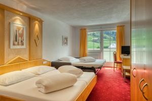 Habitación de hotel con 2 camas, escritorio y TV. en Hotel Alpen-Royal en Jerzens