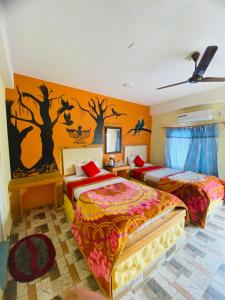 a bedroom with two beds and a wall with trees on it at Hong Qi Hotel in Chitwan