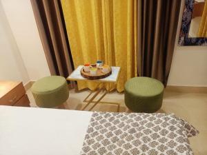 une chambre avec une table, deux tabourets et une table avec deux chaises dans l'établissement The Great Hansa INN, à Darjeeling
