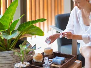 eine Frau spielt mit einem Stück Kristall in der Unterkunft Explorar Koh Samui - Adults Only Resort and Spa in Mae Nam