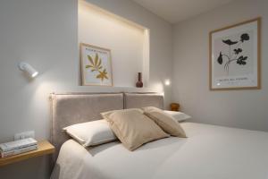 Una cama con sábanas blancas y almohadas en un dormitorio en Grotta Apartment en Vrsar