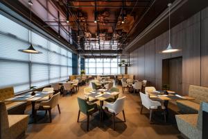 a restaurant with tables and chairs and windows at SSAW Boutique Hotel Hangzhou Chengjun in Hangzhou