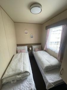 two beds in a small room with a window at Tracey and Brian's Caravan in Rhyl +8 photos