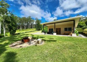 a small house with a grassy yard next to a building at Coffs Coast Mountain Retreat Cabin 2 in Coramba