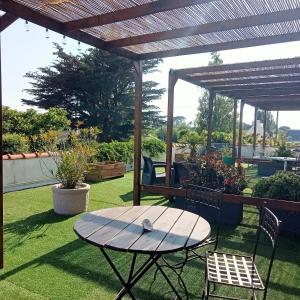 a picnic table and chairs under a wooden pergola at Les Chambres de Kerzerho in Erdeven