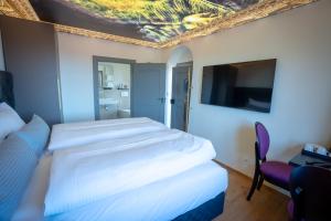 Habitación de hotel con 2 camas y TV de pantalla plana. en Maxim Suites by Elias Holl, en Augsburg