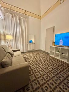 uma sala de estar com um sofá e uma televisão de ecrã plano em Casa MiRè em Catânia