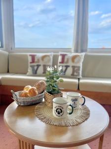 stolik kawowy z dwoma kubkami i chlebem na nim w obiekcie Domek holenderski w Rydzewie