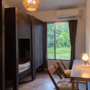 ein Wohnzimmer mit einem Tisch, einem Bett und einem Fenster in der Unterkunft the Sanctuary Kohama Retreat in Kohama