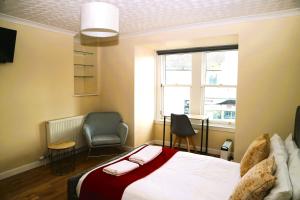 Bridge Street Guest Rooms في Tranent: غرفة نوم بسرير وكرسي ونافذة