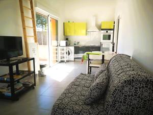 een woonkamer met een bank en een keuken bij Case Couleur proche de la mer in Brem-Sur-Mer