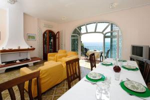 uma sala de jantar com mesa e cadeiras e uma sala de estar em Felicity: Breathtaking View On Mediterranean Sea em Maiori
