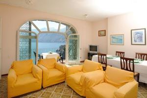 uma sala de estar com cadeiras amarelas e uma grande janela em Felicity: Breathtaking View On Mediterranean Sea em Maiori