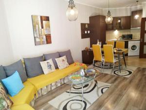- un salon avec un canapé jaune et une table dans l'établissement Cabacum Beach Residence - free parking, à Varna