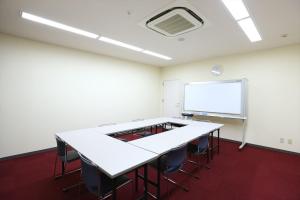 a classroom with a white table and chairs and a screen at Hotel Hokke Club Niigata Nagaoka in Nagaoka