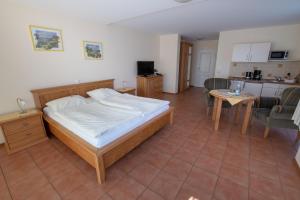 a bedroom with a bed and a table and a kitchen at Hotel und Ferienwohnung Rodenbäck in Neuharlingersiel