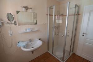 a bathroom with a sink and a shower at Hotel und Ferienwohnung Rodenbäck in Neuharlingersiel