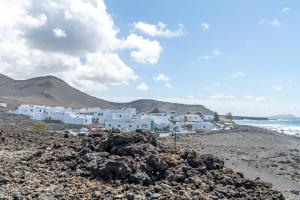 a group of white buildings on a rocky beach at Casita Isabella in El Golfo