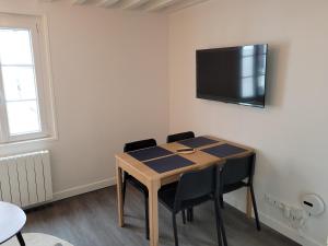 Cette chambre dispose d'une table avec des chaises et d'une télévision murale. dans l'établissement Duplex Calme et Confortable au Centre-Ville Compiègne, à Compiègne