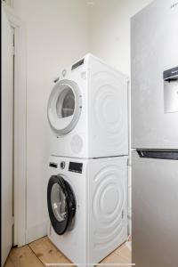 a washer and dryer in a kitchen next to a refrigerator at Blue Valley House in London