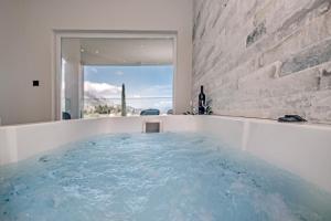 baño con bañera de hidromasaje y agua azul en Pelithea Family Aparthotel by Hotelius, en Corfú
