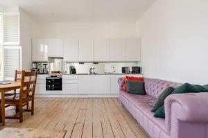 a living room with a purple couch and a kitchen at Blue Valley House in London