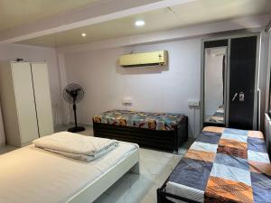 a bedroom with two beds and a fan at Ravish Apartment, Juhu in Mumbai