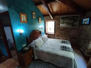 een slaapkamer met een bed met blauwe muren en een raam bij Río da Cruz in Cariño