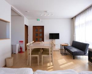 a living room with a table and chairs and a couch at FURANO BnB in Furano