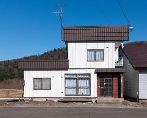 a white house with a black roof at FURANO BnB in Furano