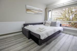 a bed in a room with a large window at Stylish 2BR Retreat - Near Station, Free Parking in Raynes Park