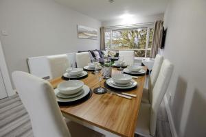 uma sala de jantar com uma mesa de madeira e cadeiras brancas em Stylish 2BR Retreat - Near Station, Free Parking em Raynes Park